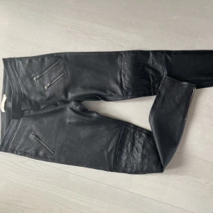 Rabens Saloner skinnbyxor  - Svarta skinnbyxor från Rabens Saloner/ Dorota. Storlek S. 3 dragkedjor fram+ gylf. Dragkedjor nertill i byxben  Tryckknapp midjan. Går precis under naveln. Fickor i sidorna. Använda 1 gång= som nya. 1000kr. Made in Portugal