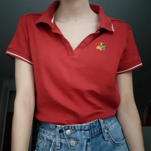 Pikétröja - Röd pikétröja från esprit som är köpt second hand som jag sen broderade Hogwartsloggan på. Den är i bra skick och tydligen i storlek XL men skulle säga XS/S
