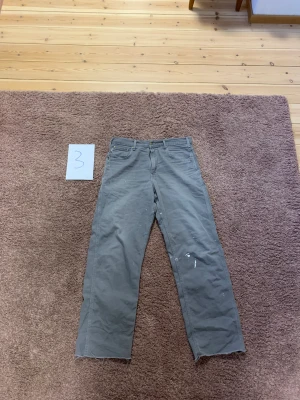 Gråa Carrhartt Carpenter - Gråa Carrhartt Carpenter med vit färgstänk på! Cond: 6/10 Waist: 41cm Length: 110cm 200kr