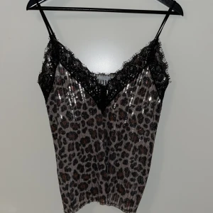 Topp med paljetter - Linnetopp med paljetter och spets🔥 Tunt material och djup urringning. Leopard mönster. Superfin och använd flera gånger. Passform är lite rakare modell och inte så åtsittande✨