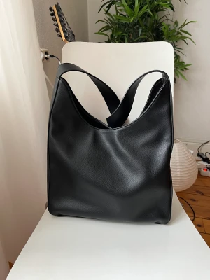 Svart handväska Åhléns  - En svart handväska från Åhléns, varsamt använd.  100% återvunnet polyester 