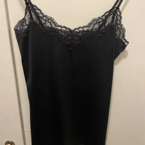 Svart satinlinne med spetsdetaljer  - Svart satinlinne med spetsdetaljer och ljusterbara axelband. Från Lindex. Aldrig använd. 