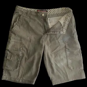 Vintage militärgröna cargo shorts, som är i bra skick. Skriv gärna innan ni köper. Midja 49 cm (går dock att justera med snörerna) Från gylfen till längst ner 39 cm.