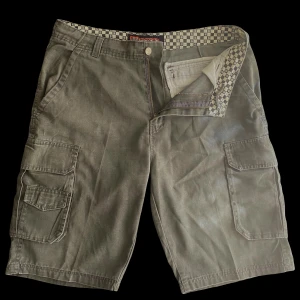 Vintage cargo shorts - Vintage militärgröna cargo shorts, som är i bra skick. Skriv gärna innan ni köper. Midja 49 cm (går dock att justera med snörerna) Från gylfen till längst ner 39 cm.