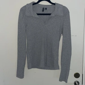 Grå tröja - En ribbad tröja från Vero Moda med en liten öppning.