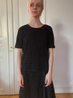 T-shirt - Svart t-shirt m seethrough-ränder.