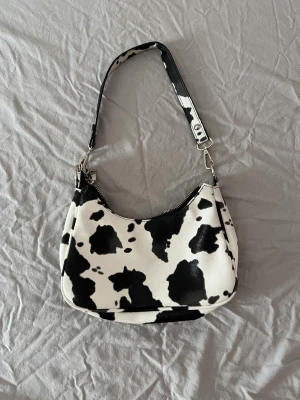 Väska - En väska i jätte coolt ko mönster. Får plats med det viktigaste och även lite till. Använts 1-2 gånger. Inga defekter. Priset går givetvis att diskutera🤍🖤 Skriv om ni har frågor 🫶🏼