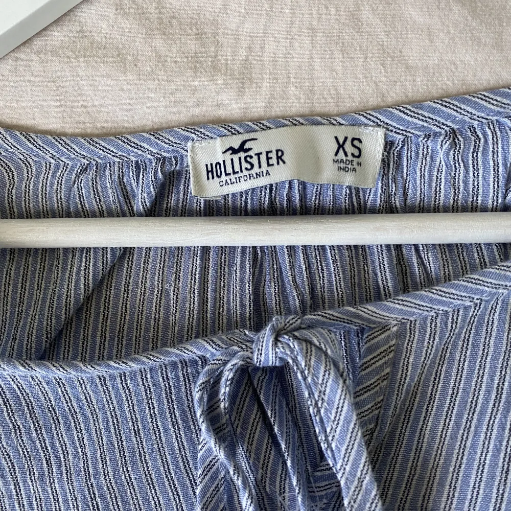 Supersöt blus från Hollister! Köpt i London och använt sparsamt. Blåvit-randig med spets i ärmarna och knytning vid halsen. Säljer eftersom den tyvärr inte kommer till användning  . Blusar.