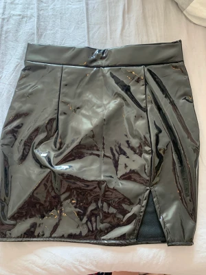 Lackkjol med liten slits - Kort lackkjol med liten slits från shein. Helt ny med lappar kvar. Storlek XS