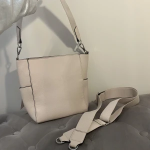 Beige läderväska med justerbar handtag - Har aldrig använts  Mått: 31cm bred och 14cm djup