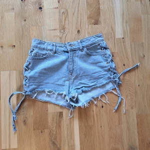 Shorts  - Denim shorts med snörningar på sidorna. Det finns en pyttteliten orange fläck som man kan se på en av bilderna, men sen syns knappt. 