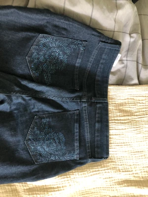 Mörkblå jeans med decorerade fickor - Y2k jeans med fina fickor, ser lite svarta ut men är blåa. Storlek 6, skriv till mig vid frågor och funderingar💓💋