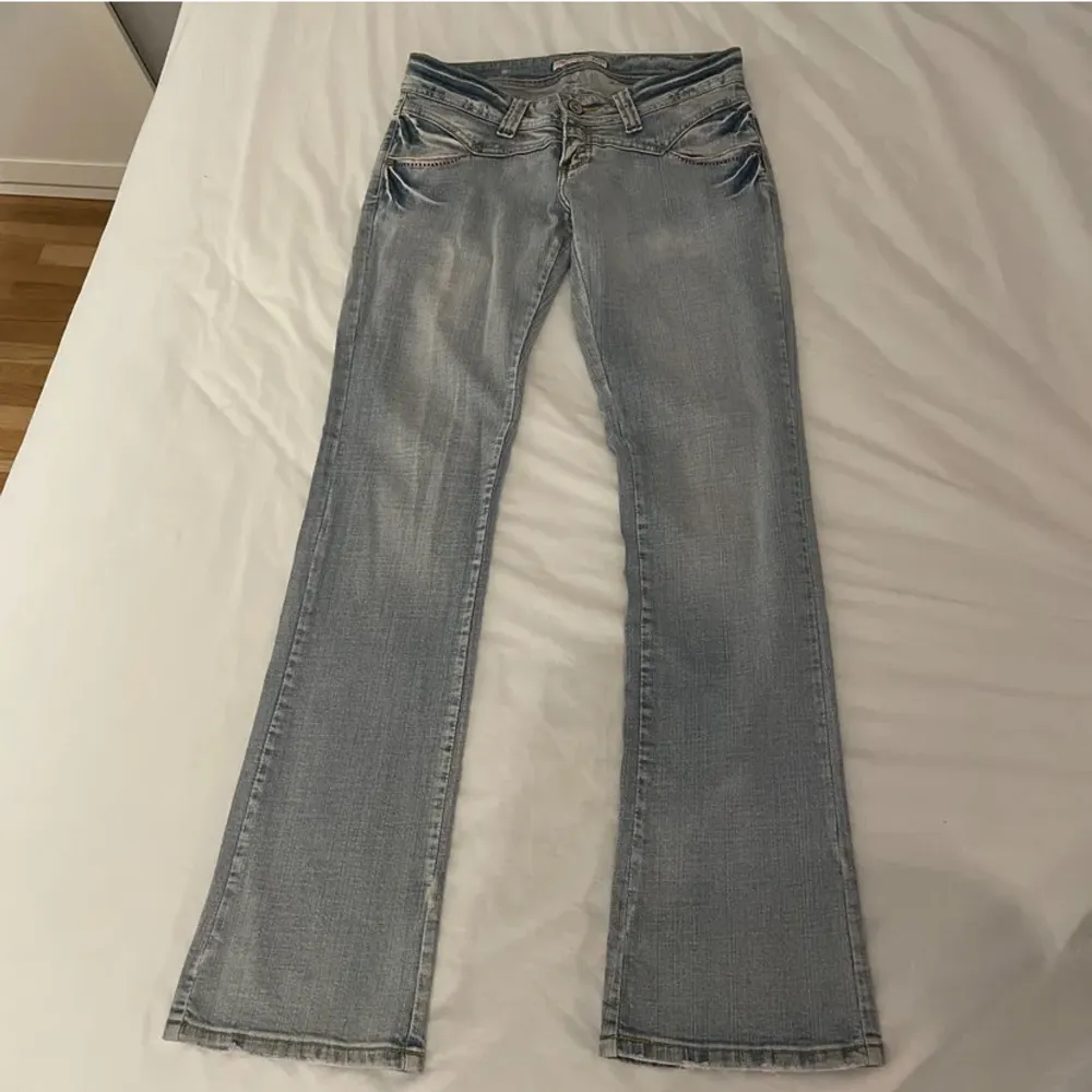 Ljusblå lågmidjade bootcut jeans storlek 38/M står det på lappen men är lite stretchiga så passar mindre också. Ifrån ett märke som heter The Queen Jeans. Cirka 87cm i innerbenslängd och 38 cm tvärs över midjan. Direktpris: 400 (+frakt). Jeans & Byxor.