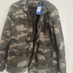 Militärgrön jacka  - En super cool jacka med militärtryck från H&M! Köpt på sellpy (Lappen kvar)! Säljes dessvärre för att jag känner att jag inte passar i den! Den är i bra skick använd 1-2 gånger! Perfekt till höst/vår!