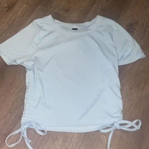 t-shirt  - använd få gånger, stretchigt material, turkosblå, rosetter nedåt 