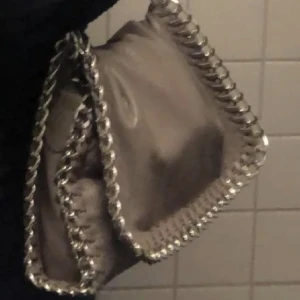 Tiamo väska grå - Säljer min tiamo väska då den inte längre kommer till så mycket användning , kedjan och väskan är hel inga skador osv men som ni kan se på bilden är den använd en hel del men personligen tycker jag det är finare än nya.skickar gärna egna tydligare bilder❤️