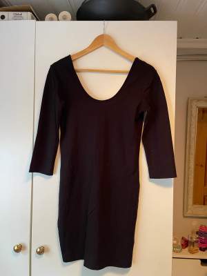 En svart klänning med en liten urringning bak och fram. Storlek: L. 