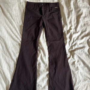 Lågmidjade kostymbyxor - Lågmidjade bruna kostymbyxpr med bootcut köpta från Urban Outfitters för cirka 2 år sedan. Endast testade av mig därav prislapp. Bara att skriva vid frågor! Köparen står för frakt.