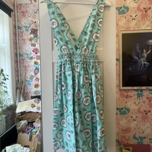 Hängselkjol - Kjol/klänning med korsade band k ryggen och elastisk midja, inga fläckar och resår i midjan. Kjolen går ner till knäna, (jag är 171 lång)