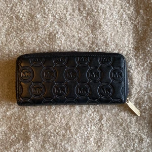 Michael Kors plånbok  - Rymlig svart plånbok från Michael Kors. Använd ett fåtal gånger. Har legat i min byrålåda dom senaste åren och söker nu en ny ägare. 