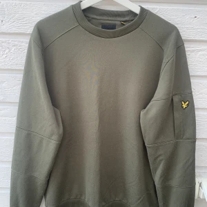 Lyle & Scott tröja - Grön långarmad tröjo med Lyle & Scott märke på armen med en liten ficka