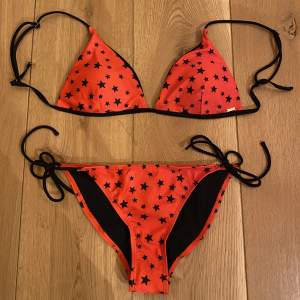 Säljer en röd bikini med svarta stjärnor på från loavies. Den är helt oanvänd (lappen på underdelen finns kvar), jag har bara klippt bort lappen på överdelen. 