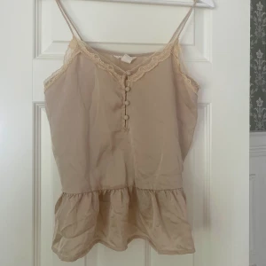 Söt beige topp - Topp från hm i superfint skick! Söta klädda knappar, liten peplum och spets i en fin beige färg 🥰