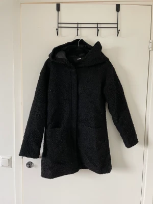 Svart kort kappa med luva - Svart kort kappa, men luva. ”Fnasigt” material. Från Bikbok