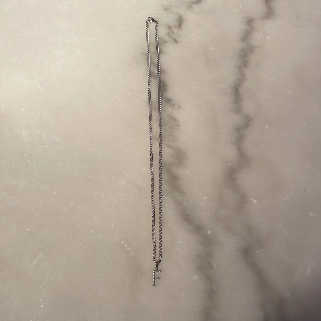 Halsband med ett silver ”F”