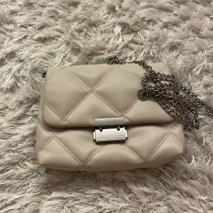 Handväska  - En handväska som är liten och har en lång kedja som man inte in ta av. Säljer pågrund av ingen användning, men jättefin. Står ej för frakt.