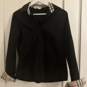 Burberry Skjorta - Säljer nu denna asfeta burberryskjorta då jag har växt ur den! Den är i storlek 38 som motsvarar S/M. Skicket skulle jag säga är 9/10 då den endast är använd fåtal ggr! Hör av dig om du har några funderingar! ☺️☺️