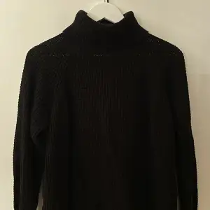 En stickad tröja med polokrage i färgen svart. Från ellos strl 38-40.