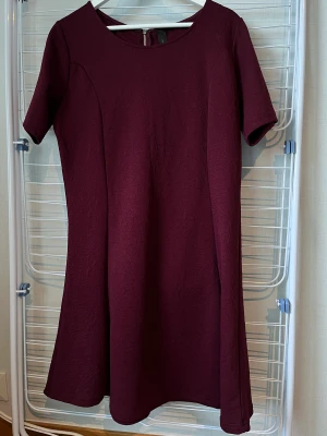 Finklänning - Vinröd/lila klänning från Geena. Lätt broderat blommönster. Mycket bra skick!