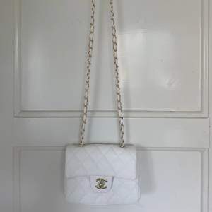Chanel inspirerad väska i vit med gulddetaljer. Aldrig använd så är i nyskick.