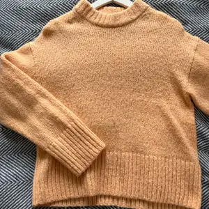 En peach färgad stickad tröja från Gina tricot med vida armar och detaljer längst ned på tröjan. Oanvänd och helt intakt! 
