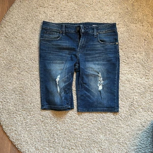 Jeans-shorts Guess 30 - Jeansshorts från Guess med div hål i (förhandsgjorada) använda men i fint skick. 30 i midja