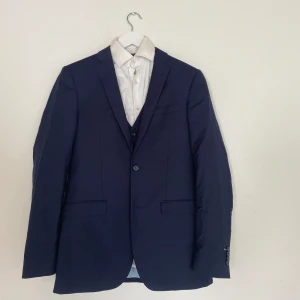 Moods Of Norway Kostym - Mörk blå Moods Of Norway kostym inkluderad skjorta.  Kavaj storlek: 46 Vest storlek: 46 Skjorta storlek: XS Byxor storlek: 46 Kontakta mig om intresserad 