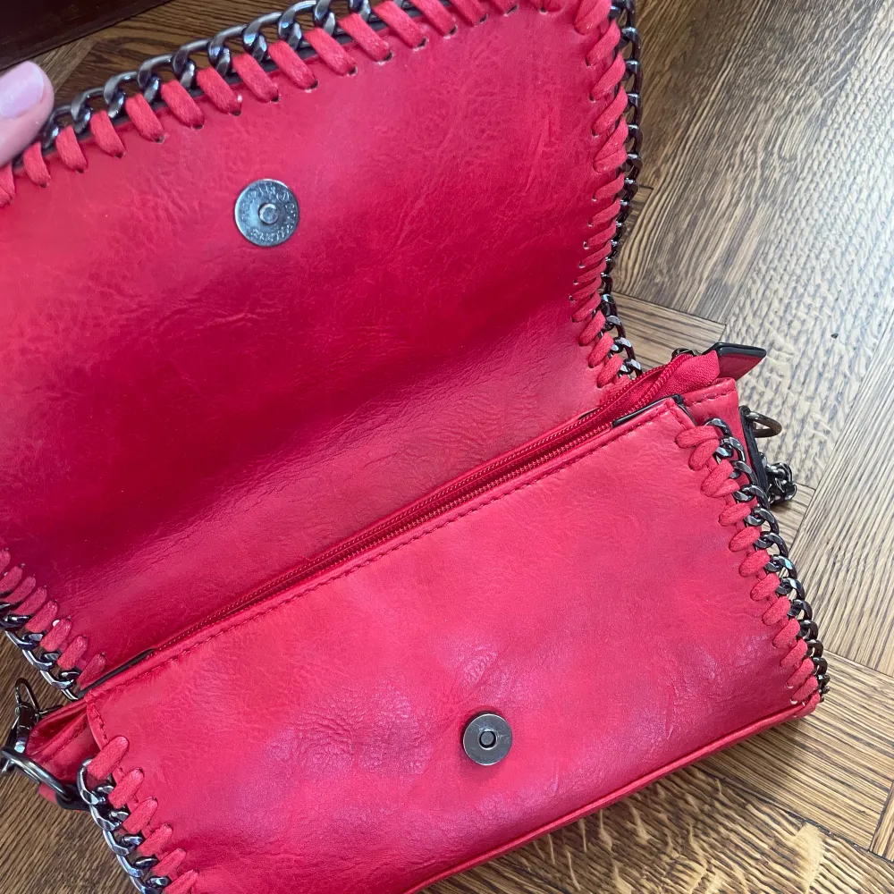 Röd väska med kedja, vet ej märke men köpte den i affär ny och har används några ggr. Finns små defekter, skriv privat för bilder. Bredd 26cm höjd 16cm. Väskor.