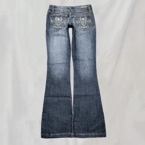 Lågmidjade jeans - Midja:ca69 innerben:ca81 Jeans med detaljerade bakfickor i bootcutmodell. Storlek "0", uppskattar passa en XS. Något tunnare I materialet. Lite smånötningar enligt bilder. Något nötta lite "nertrampade" fotändar. Överlag fint skick!🤍