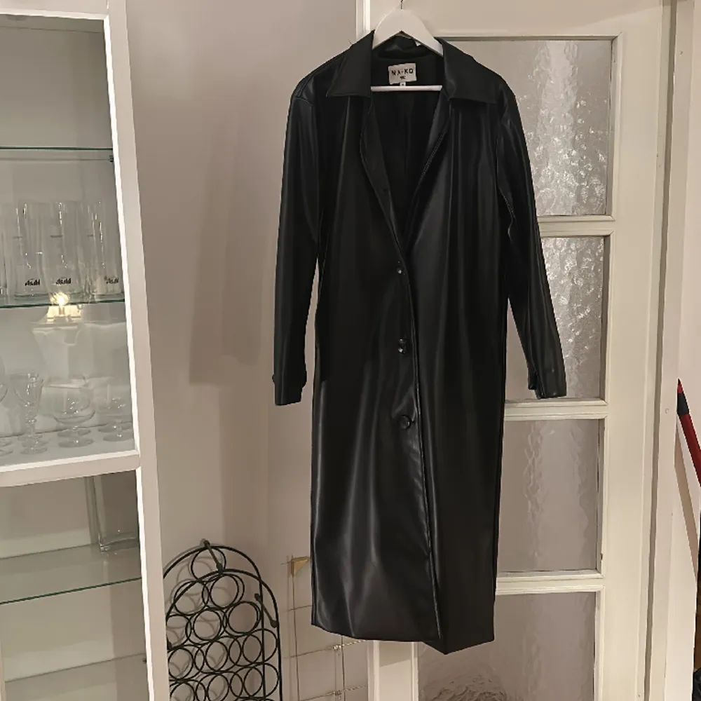 Long, PU trench coat for women. Size 36. Barely used but has a little whole on the right sleeve from a cigarette, barely seen tho. Original price 1200kr. Takit.