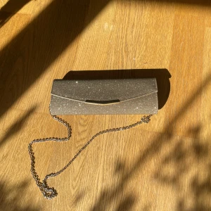 Guldig väska - Glittrig och guldig kuvertväska med kedja. Kedjan kan man även ha inne i väskan eller ta av om man vill hålla i den istället. Mycket bra skick!💕