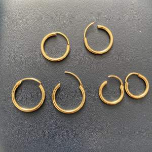 Oanvända guldiga örhängen i olika storleker