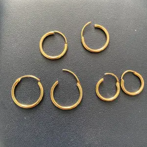 Oanvända guldiga örhängen i olika storleker