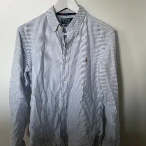 Säljer denna Ralph lauren skjorta i randig blå och vit.