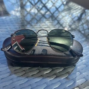 Vintage Ray-Ban Round Metal - B&L Ray-Ban i Round Metal modellen  Storlek: Small Färg: Gun Metal Black Modell nummer: w1574  Skick: I hyfsat bra skick, en liten repa på den vänstra linsen och små skador på öronstöden men annars inget anmärkningsvärt  Skriv gärna vid frågor!