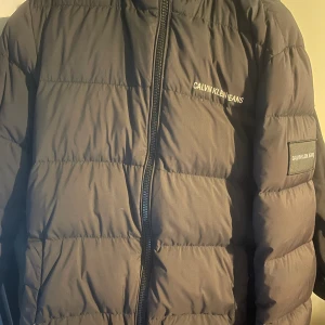 Calvin Klein jacka - En superskön dunjacka som passar alla. Det finns ett litet skav vid ena fickan. Och en knapp på luvan har lossnat men syns inte. I övrigt är jackan riktigt fin. 8/10. 