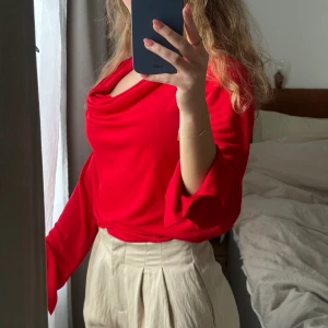 Draperad blus långärmad blus från STOCKH LM - Nyskick. Använd en gång. Fint draperad blus med utsvängda ärmar i skönt svalkande material. Romantisk röd färg.