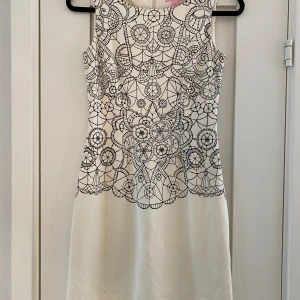 Vit klänning med svart mönster i strl XS från Lilly Pulitzer modell Julianna dress lace you there - Endast använd en gång.  Tyvärr finns där en fläck på framsidan och en prick längst ner på baksidan  Mått Över bröstet: ca 39 cm Total längd: ca 84 cm  Rayon, polyester och elastan  Kommer från ett djur och rökfritt hem.