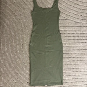 Grön midi klänning - Tight klänning från Zara med en slit på baksidan. Klänningen är i nyskick och har använts kanske ett par gånger. 