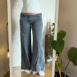 Gråa lågmidjade byxor - Gråa byxor med låg midja och fina detaljer. Bra skick, endast lite slitningar längst ner vid byxbenen. Sitter bra på mig som är 172cm. Köpta vintage. 97% cotton 3% spandex Size 9  